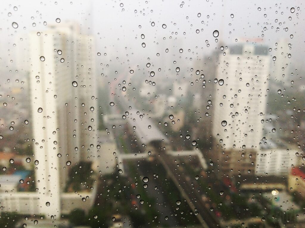 雨の日の窓ガラスに流れる水滴と街の景色