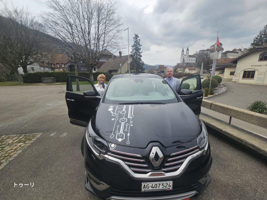 Guests beside the private vehicle in a Swiss village, with their suitcases still in the car