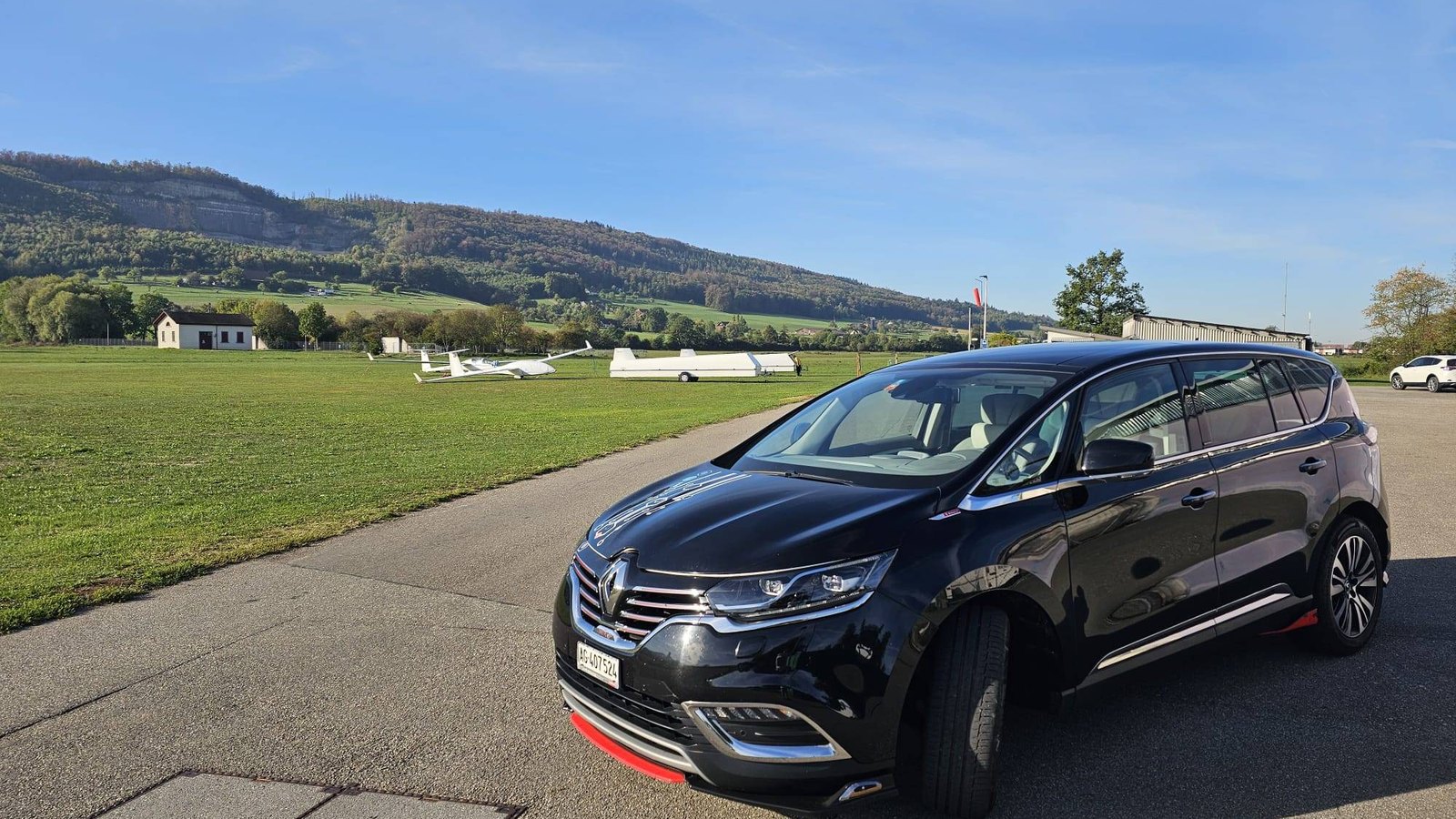 ツアーで使用する専用車 Renault Espace Initiale（黒）の外観。スイスの飛行場の脇で撮影。